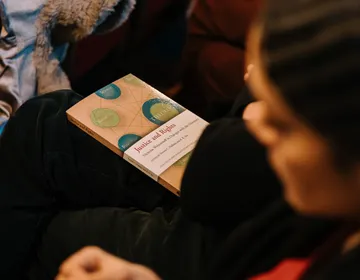 An attendee holding a copy of Justice and Rights: Nicholas Wolterstorff in Dialogue with the University.