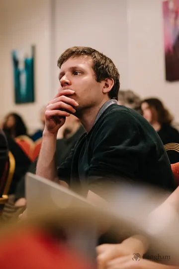 A graduate student listening closely from the audience.