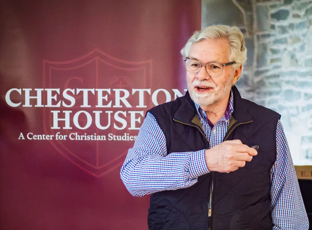 A speaker presenting in front of the Chesterton House banner at Cornell’s Center for Christian Studies.